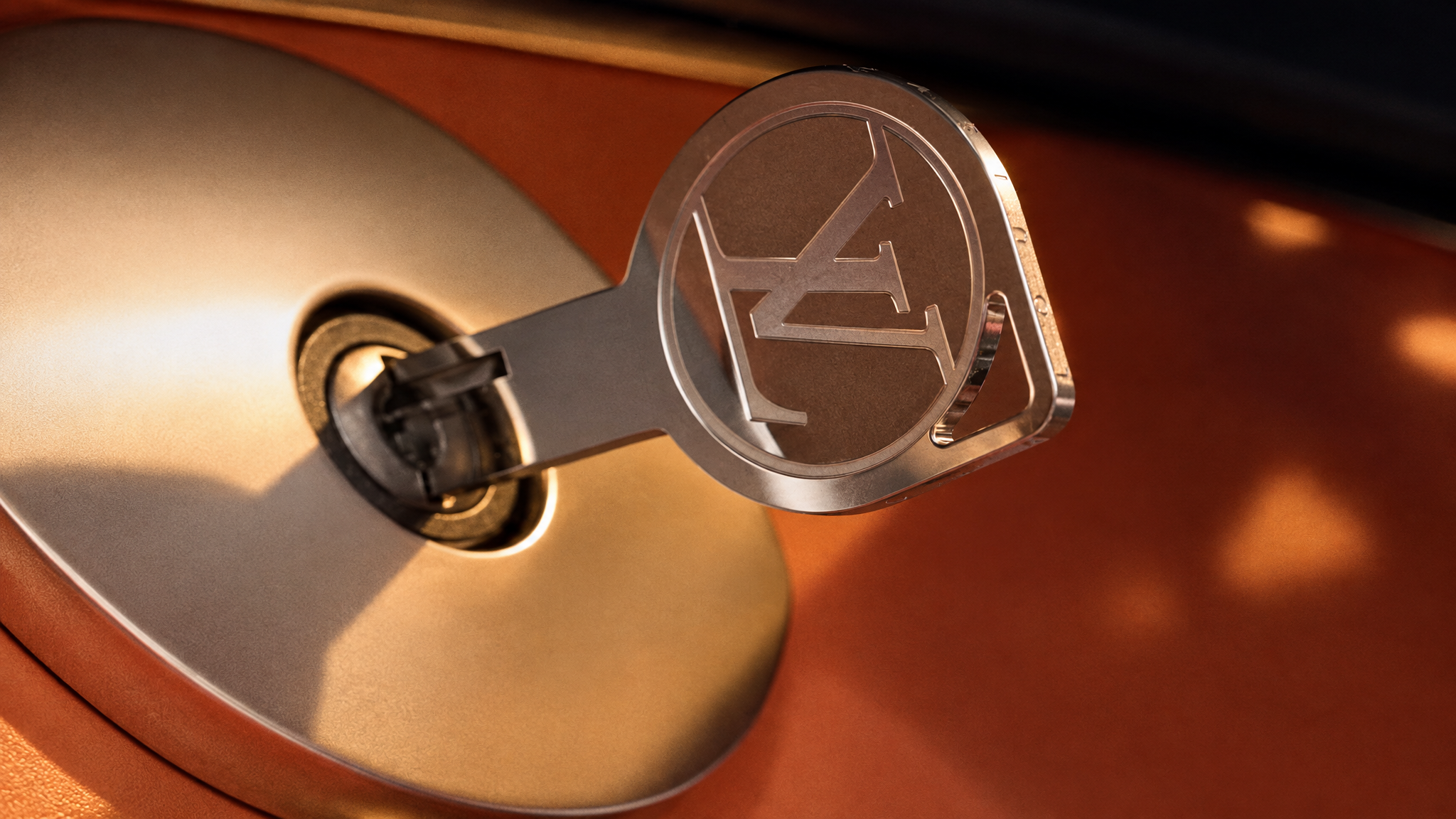 Close-up of an LV key and lock against warm metal and leather.